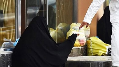Person handing cash to a roadside beggar.