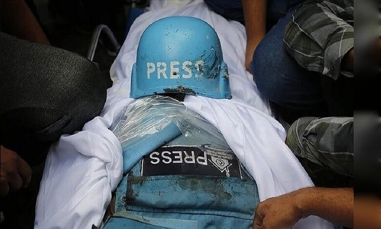 Protester wearing a blue helmet and press badge during a demonstration, surrounded by people.