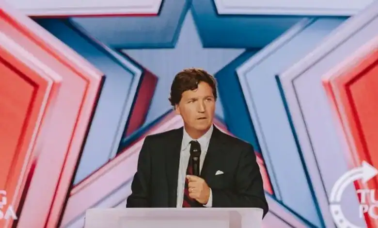 Podcast host Tucker Carlson speaks at a podium during Turning Point’s AmericaFest conference in Phoenix, Arizona.