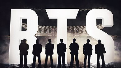 K-pop stars standing on stage during a comeback event, silhouetted against bright lights.