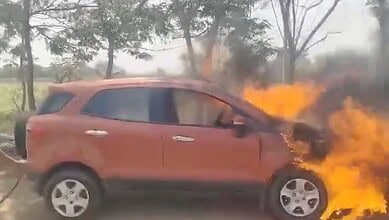 Car on fire during an accident, with flames and smoke.