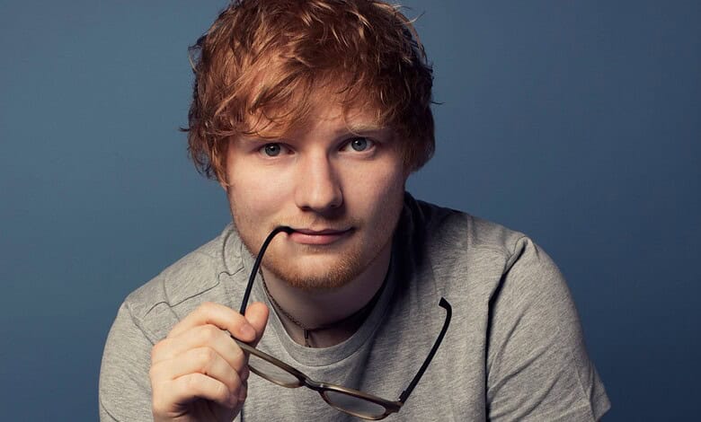 Ed Sheeran with glasses, reflecting on a difficult day, in a close-up portrait.