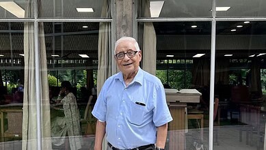 HK Dua, renowned journalist and diplomat, smiling in a light blue shirt at a public event.