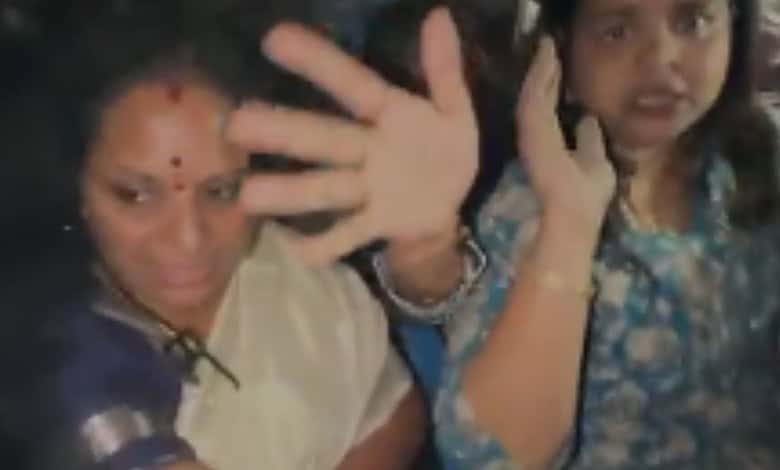 Kavitha protesting with a raised hand and a phone, expressing opposition to construction activities on th.