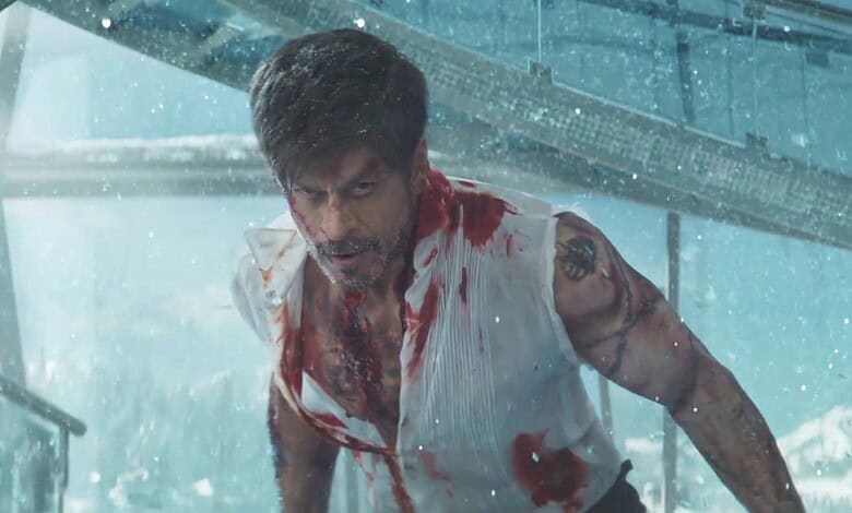 Action scene from a movie featuring a man with bloodstains on his shirt, intense expression, and a rainy.