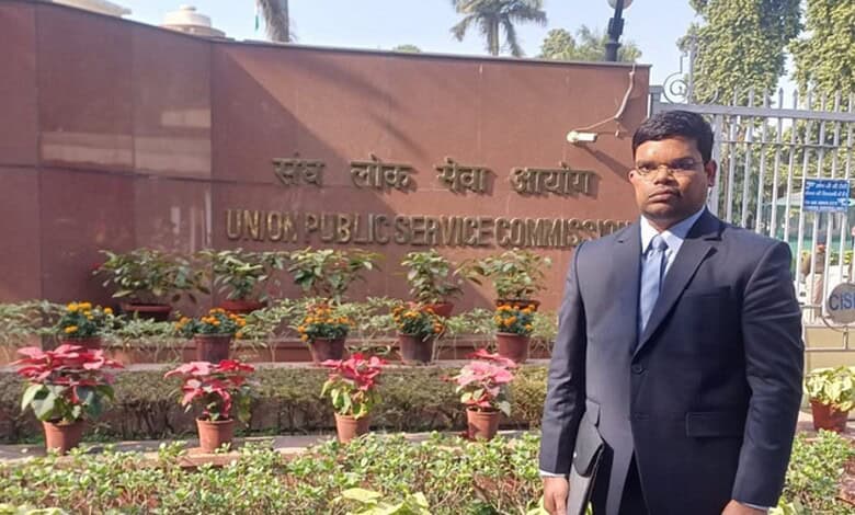 Man in formal suit standing outside Union Public Service Commission building in India.