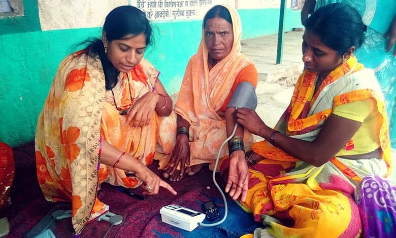 Women receiving blood pressure measurement at a health camp.