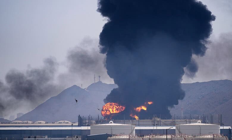 Fire and smoke at Fujairah oil storage facility after Iran's attack, with mountains in the background.
