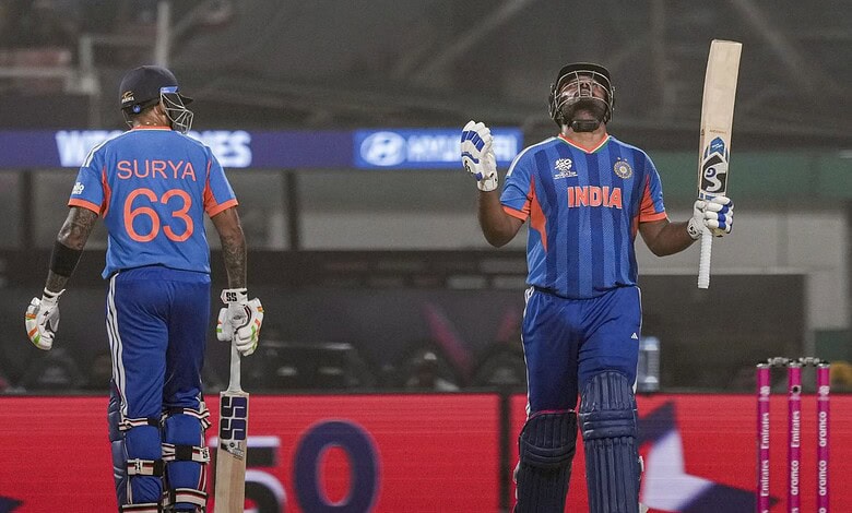 India players in blue jerseys, one raising bat in victory, stadium background.