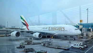 Emirates Boeing 777 aircraft parked at Dubai International Airport terminal.