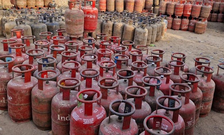 Large collection of red LPG cylinders stored outdoors in a yard.