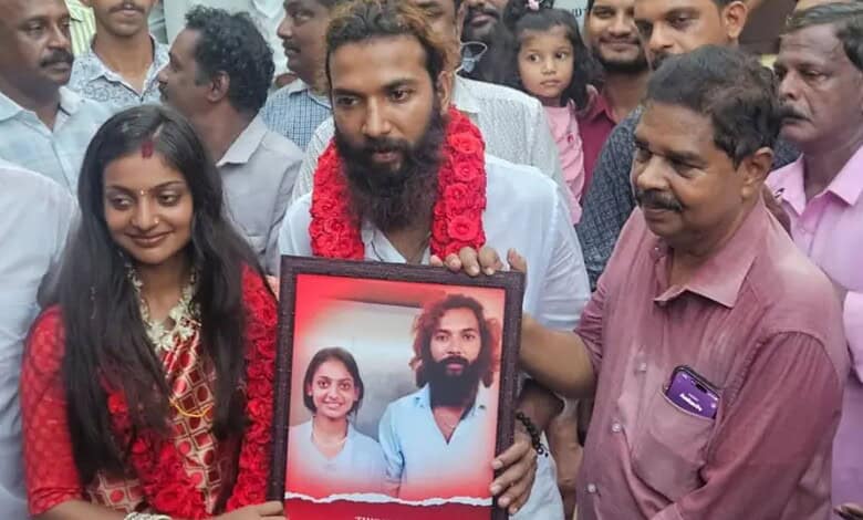 A man holding a framed photo of Monalisa Bhosle, surrounded by friends and family during her wedding at T.