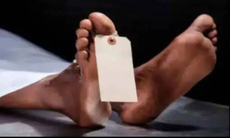 Hand holding a blank tag with feet in the background, related to Telangana murder case.