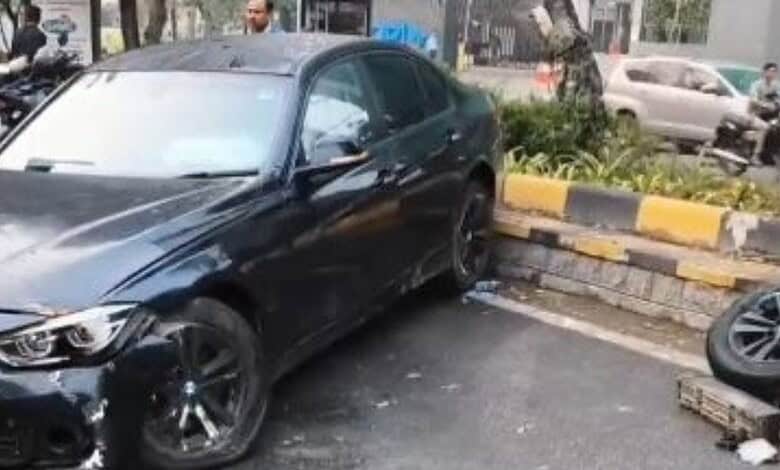 Black BMW sedan involved in a collision with the median on a city street in Hyderabad.
