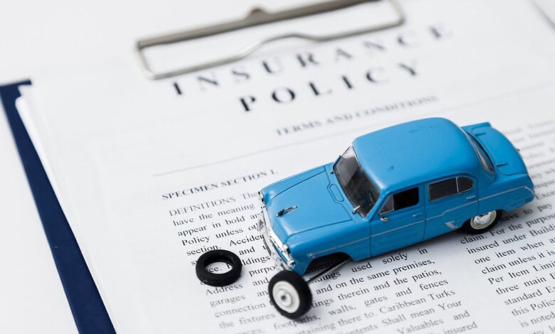 Car insurance policy document with a toy car and a tire on top.