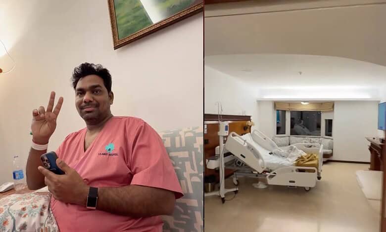 Zakir Khan in hospital room making peace sign, hospital bed and medical equipment visible.