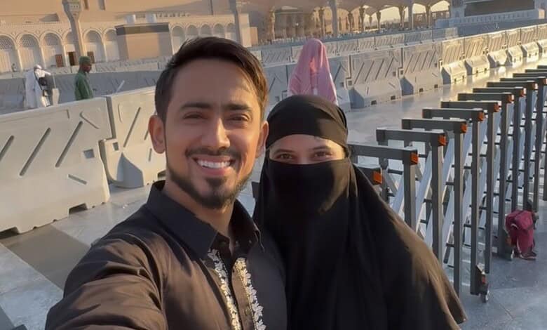 Happy couple taking a selfie at a mosque, celebrating conversion to Islam before marriage.