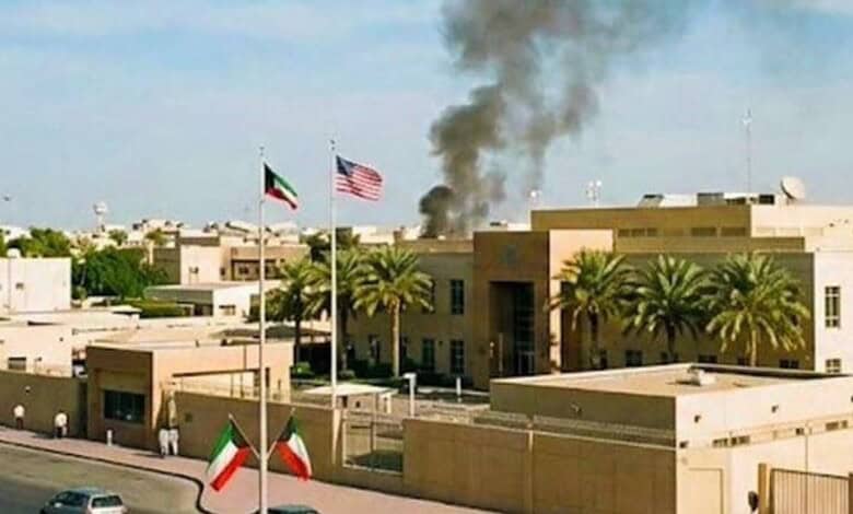Black smoke rises near the US embassy compound in Kuwait as American and Kuwaiti flags fly outside the building.
