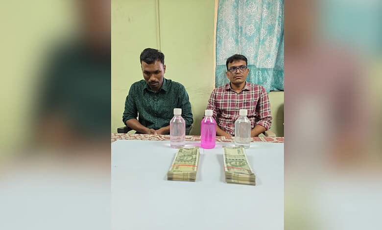 Two police officers caught taking a Rs 1 lakh bribe, with cash and bottles on the table, in Malkajgiri.