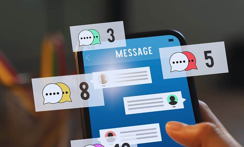 A person holding a smartphone displaying numerous chat alerts, highlighting ongoing suspicious messaging activity linked to Pakistani phone numbers.