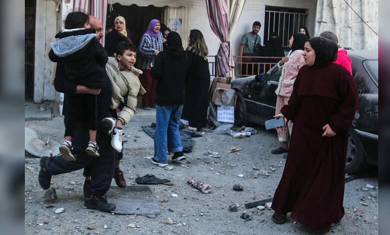 A man carries two children while residents flee after an Israeli strike hit a neighbourhood in Mieh Mieh near Sidon, Lebanon, on March 13, 2026.