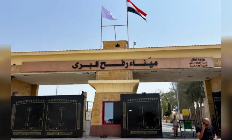Egyptian side of Rafah border crossing gate with flags and security post.