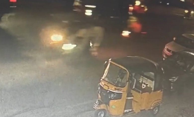 An auto rickshaw and vehicles on a street at night, with blurred lights and a smoky atmosphere, related t.