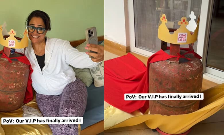 A woman holding a phone and smiling next to a large LPG cylinder with a humorous crown label, highlightin.