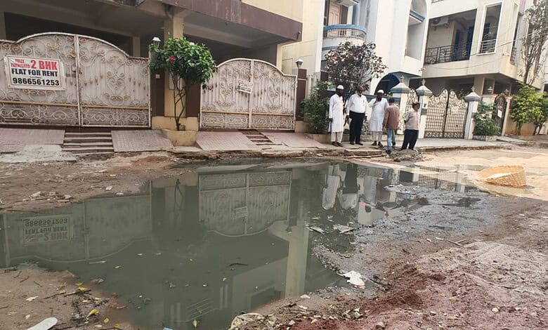 Flooded street with dug-up roads and residents raising alarm in Tolichowki.