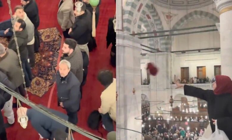 Woman throws headscarf from upper level during protest at Istanbul’s Fatih Mosque as men look on below.