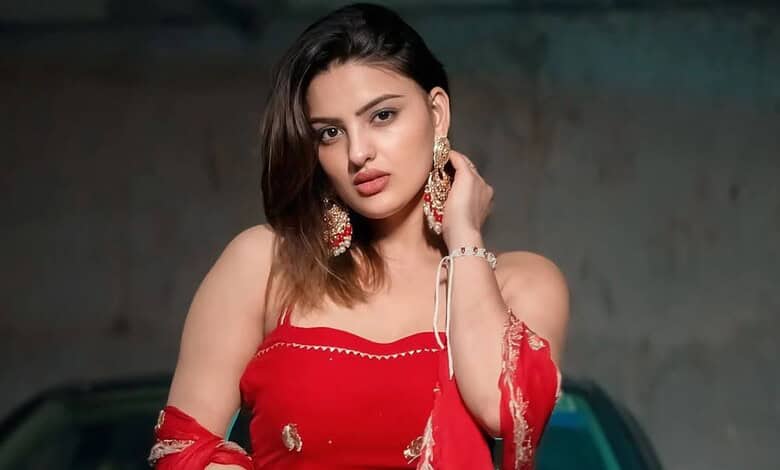 Portrait of Divyanka Sirohi, a Haryanvi actress, wearing a red outfit with earrings.