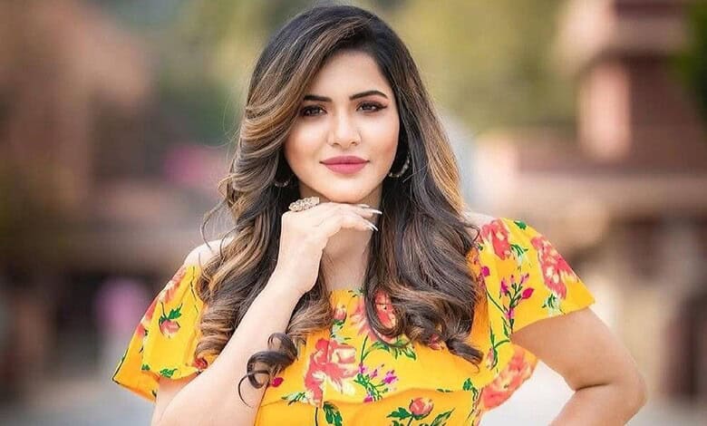 Ashu Reddy posing confidently outdoors, showcasing her vibrant attire and glamorous look.