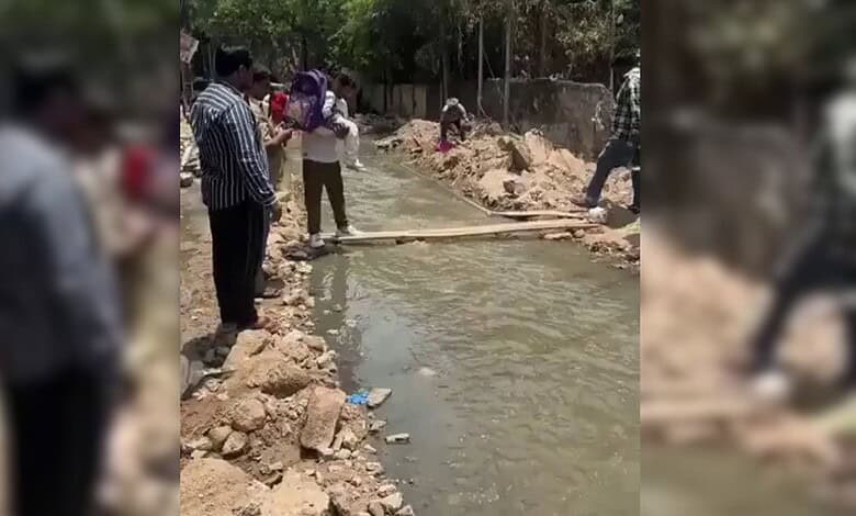 Locals crossing a nala in Banjara Hills using wooden planks during flood conditions.