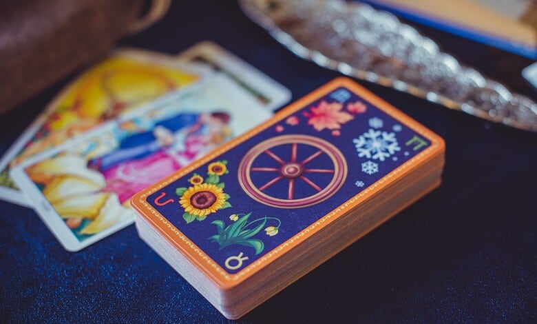Tarot card deck with colourful designs on a table, surrounded by tarot cards and crystals.
