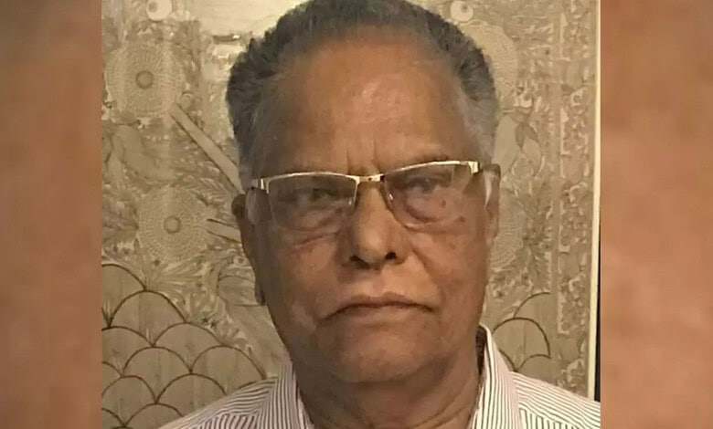 Close-up of an elderly Indian man wearing glasses and a striped shirt.