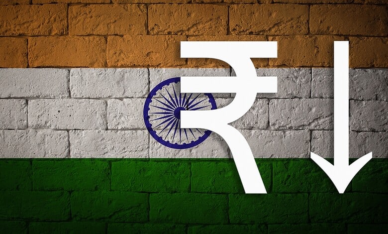 Illustration of Indian Rupee symbol with downward arrow on Indian flag background.