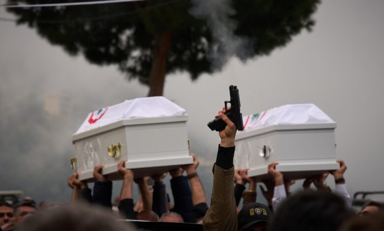 A gunman fires his gun as men carry the coffins with the bodies of Pierre Mouawad, an official with the anti-Hezbollah Lebanese Forces party, and his wife during their funeral in Yahshush, in Lebanon on Tuesday, April 7.