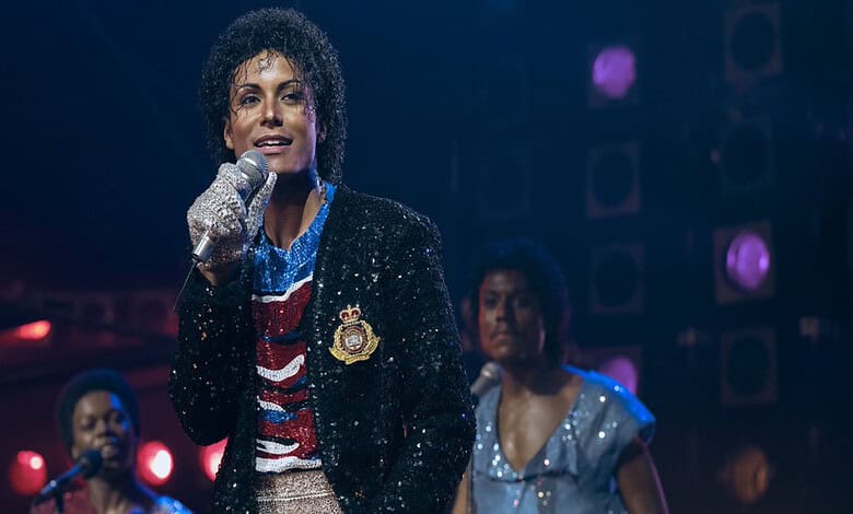 Actress portraying Michael Jackson in a biopic performs on stage with microphone, dressed in iconic style.