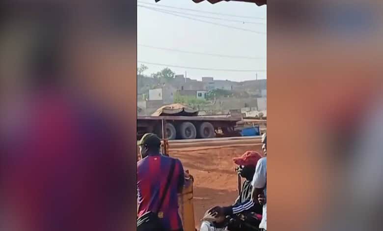 Explosion site in Mali with military vehicles and civilians nearby.