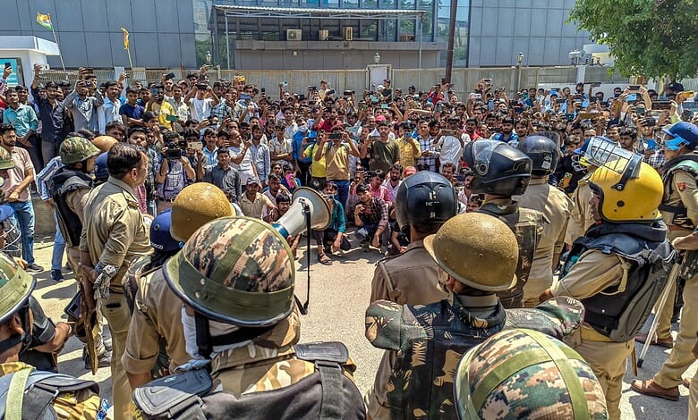 Security personnel stand guard as factory workers stage a protest demanding a hike in wages, in Noida, Gautam Buddh Nagar district, Uttar Pradesh, on April 13. The protest carried incidents of arson, vandalism and stone-pelting reported from Phase-2 and Sector 60 areas, police said.