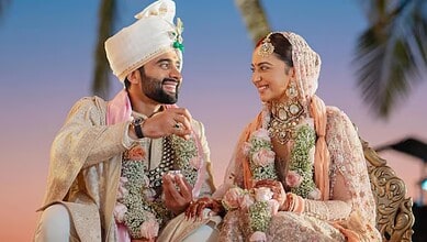 Wedding couple in traditional attire celebrating outdoors at sunset.