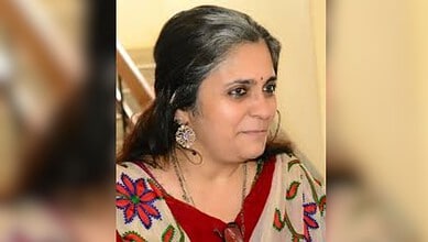 Indian woman in traditional attire with earrings, looking to the side, indoors.