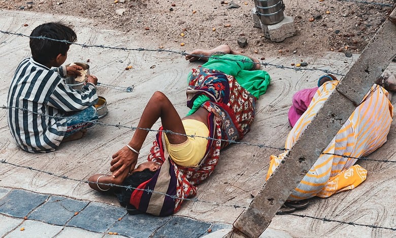 Child begging on the street, sitting near a woman lying on the ground, highlighting social issues and cas.