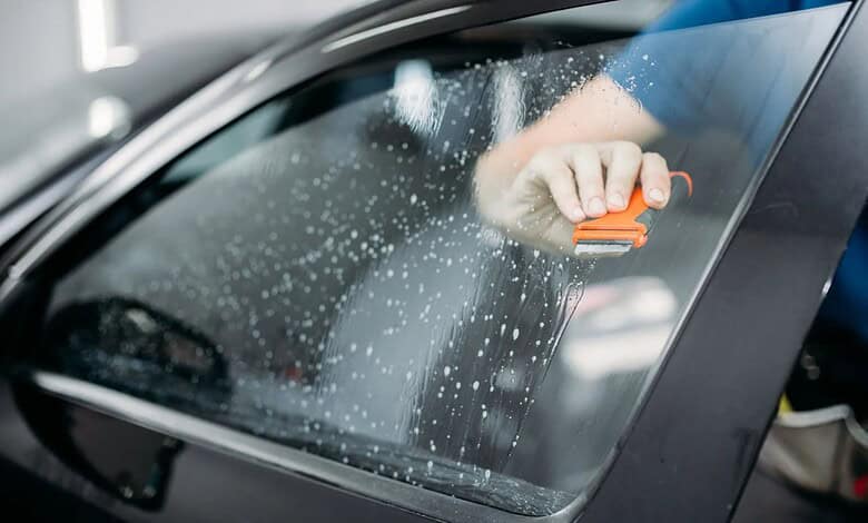 Officer cleaning car window as part of Hyderabad crackdown on tinted glass and black films.