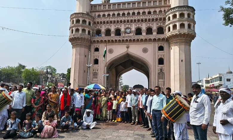 Crowds celebrating a tribal festival at Charminar with traditional music and dance.