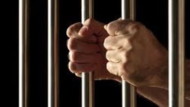 Hand gripping prison bars, symbolising drug busts and law enforcement action in Telangana.