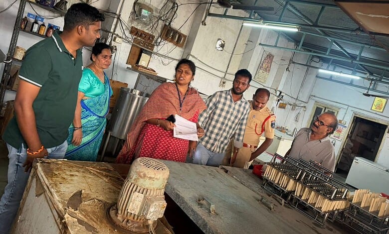 People inspecting sweets in a bakery workshop with large containers and equipment.