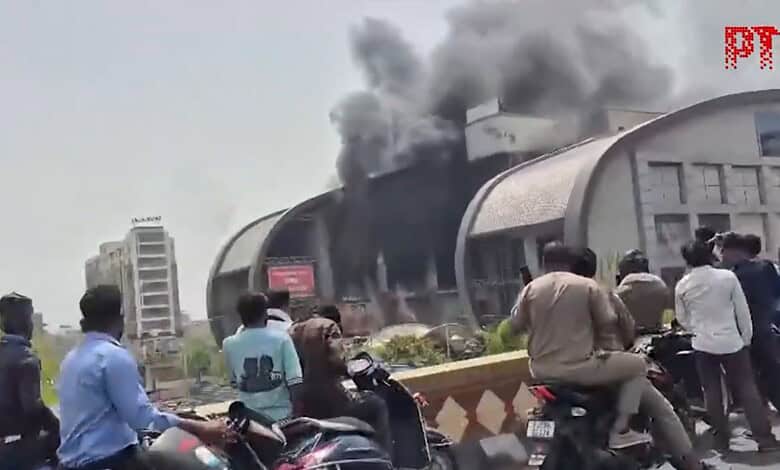 Large fire engulfs Kota's City Mall with thick black smoke, people watch as emergency services respond.