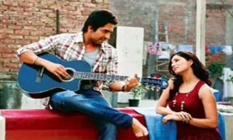 Yami Gautam playing guitar on set, smiling at co-star in a casual outdoor scene.