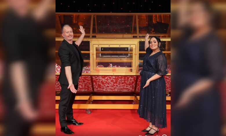 Big Ticket Abu Dhabi hosts Richard and Bouchra Yamani stand beside the raffle draw machine on stage.